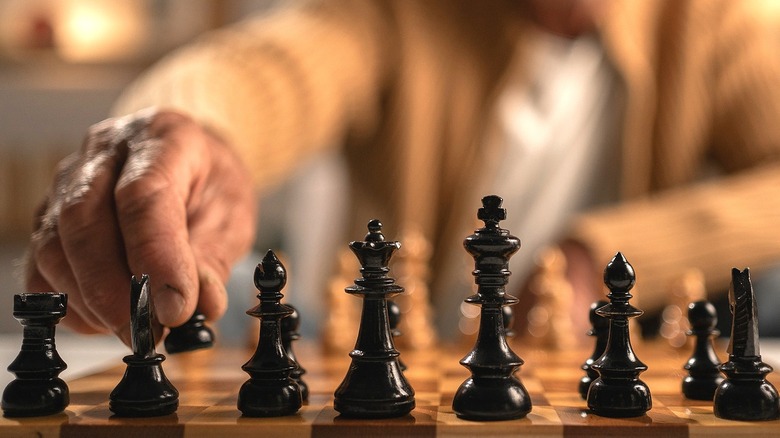 Zoom in on a person's hand making a move on a chess board